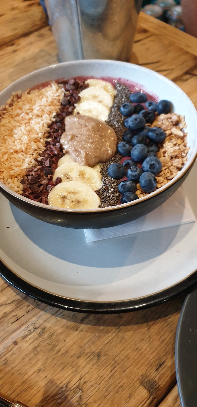 Açai smoothie bowl with banana, blueberries, granola, coconut, cacao nibs, chia and almond butter